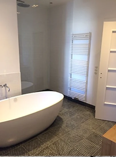 Freistehende Badewanne in einem hell gefliesten Badezimmer