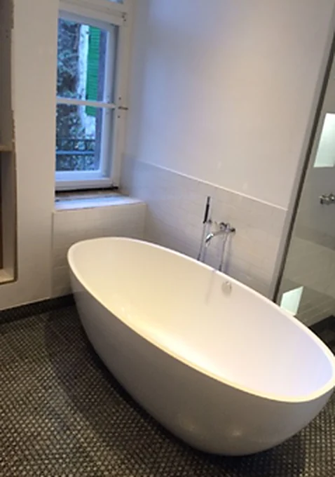 Badewanne am Fenster mit Natursteinboden und Wandnische