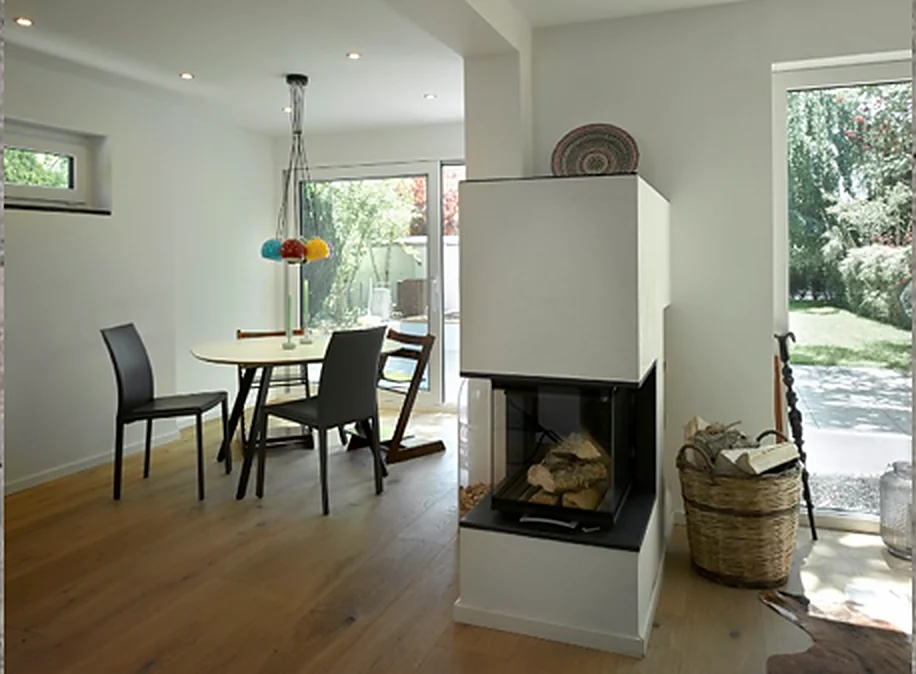 Wohnbereich mit Kamin, Esstisch und geöffneter Terrassentür