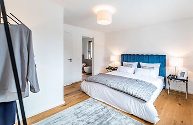 Schlafraum mit Bett, Eichenparkett und weichem Tageslicht